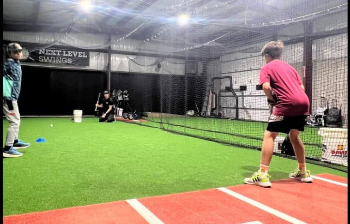 A player taking swings in a Next Level Swings batting cage